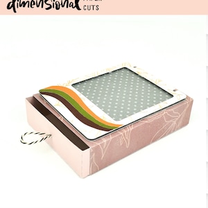 May include: A pink and white matchbox with a pull-out drawer. The box has a window with a grey and white polka dot pattern. The window is framed with a white border and a brown, orange, and yellow wavy design. The text "GROOVY MATCHBOX SVG" is printed below the box.