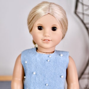 May include: A doll with blonde hair wearing a light blue sleeveless dress with white pearl embellishments.
