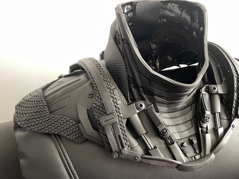 May include: Black plastic neck and shoulder armor with a textured surface and multiple adjustable straps.