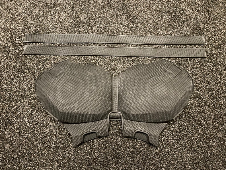 May include: A black foam chest piece with a textured surface. The chest piece is designed to look like a superhero's chest plate.