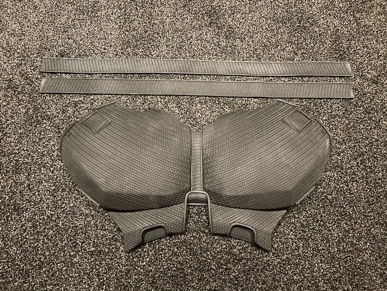 May include: A black foam chest piece with a textured surface. The chest piece is designed to look like a superhero's chest plate.