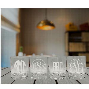 May include: Four clear glass tumblers with a monogram design. Each tumbler has a different monogram, including "ABC", "AMT", "CSS", and "S&S".