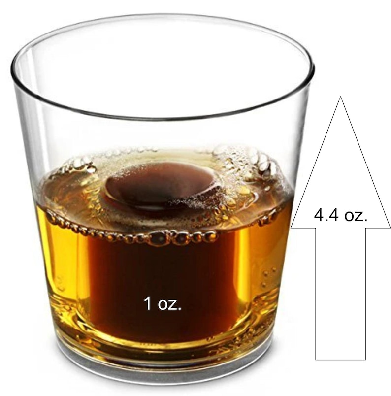 May include: A clear glass filled with a dark amber liquid and a brown ice sphere. The image shows a 1 oz. measurement at the bottom and a 4.4 oz. measurement indicated by an arrow.