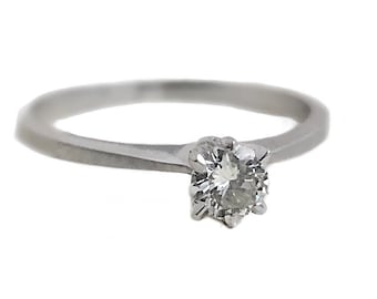 May include: A simple silver band ring with a single round diamond set in a prong setting.