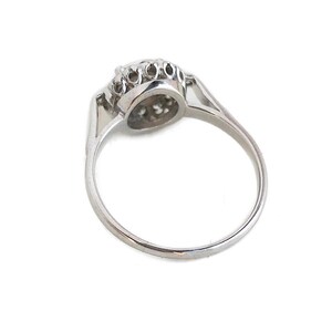 May include: A silver ring with a round, clear stone surrounded by smaller stones.