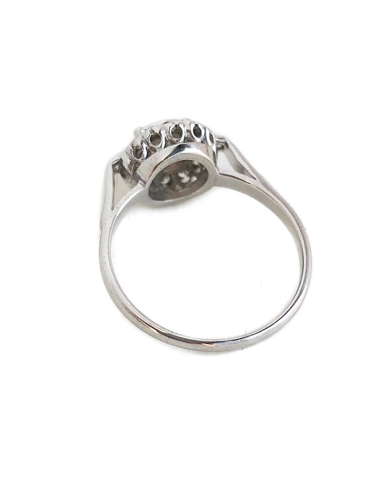 May include: A silver ring with a round, clear stone surrounded by smaller stones.