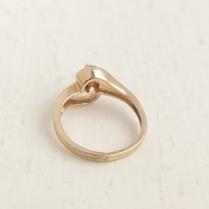 May include: A gold ring with a single stone set in a heart-shaped design.