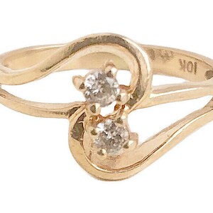 May include: A gold ring with two small diamonds set in a heart shape. The ring is marked "10K" on the inside.