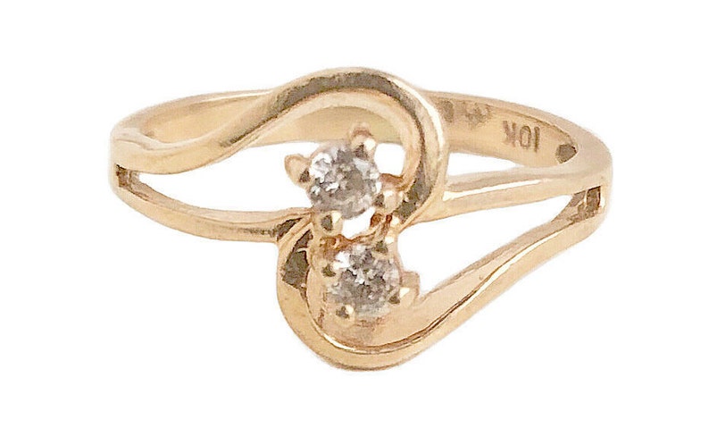 May include: A gold ring with two small diamonds set in a heart shape. The ring is marked "10K" on the inside.