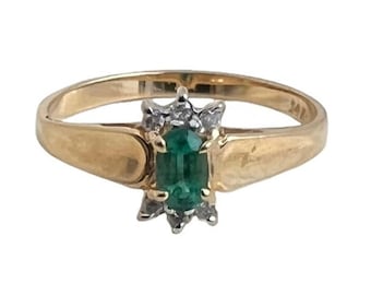 May include: A gold ring with a green emerald gemstone surrounded by small diamonds.