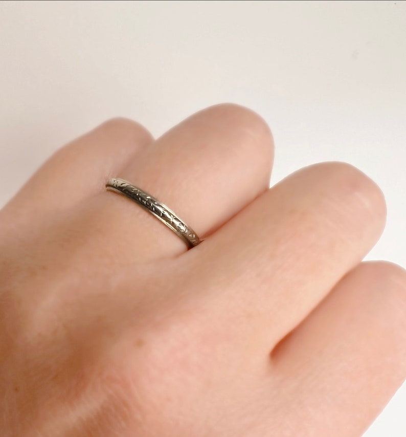 Pode incluir: Um anel de banda de prata simples com um design gravado delicado.