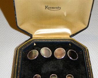 May include: A black octagonal box with a gold trim and a velvet interior. The box contains seven round, black and white cufflinks with a silver rim. The box is labeled "Krementz".