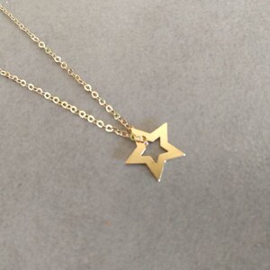 May include: A gold chain necklace with a star pendant. The star has a cut-out design in the center.