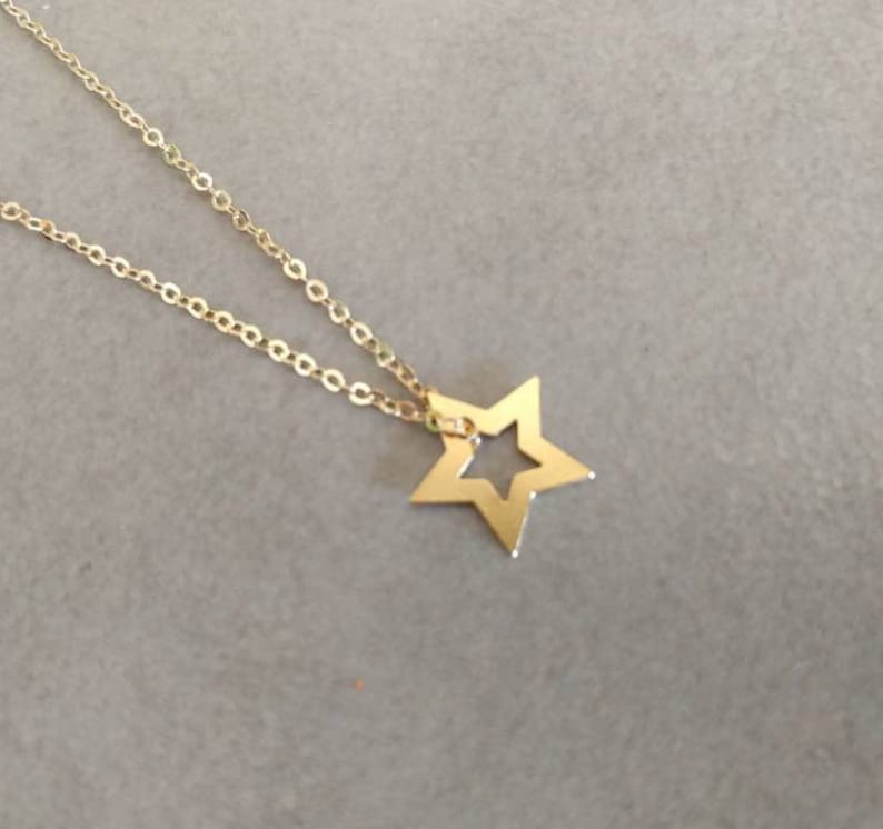 May include: A gold chain necklace with a star pendant. The star has a cut-out design in the center.