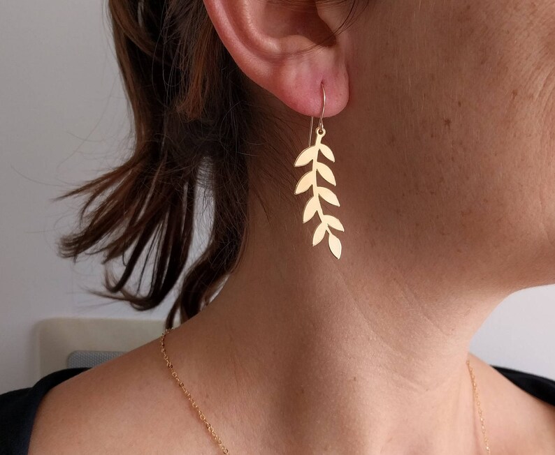 Pu&ograve; includere: Orecchini a foglia d'oro con un delicato design a ramo. Gli orecchini sono lunghi e pendono dal lobo dell'orecchio.