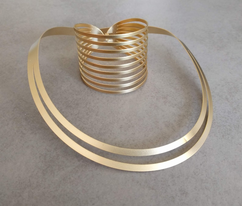 May include: A gold-toned metal necklace with a thick, double-layered chain and a matching, multi-layered cuff bracelet.