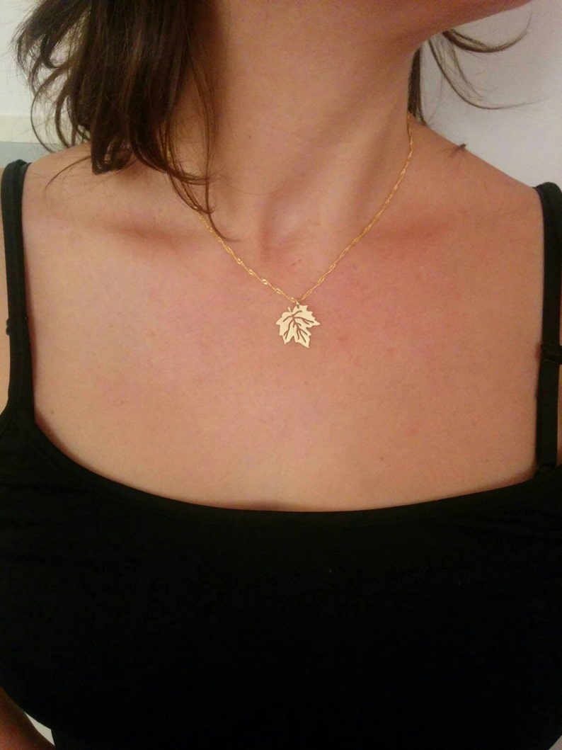 Puede incluir: Un collar de cadena de oro con un delicado colgante de hoja.
