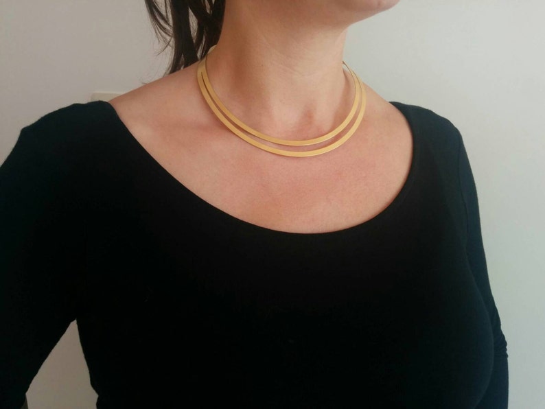 May include: A gold-toned double-layered choker necklace. The necklace is made of two thin, flat bands of metal.