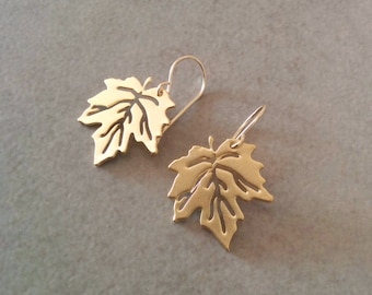May include: A pair of gold-tone earrings featuring a delicate maple leaf design. The leaves are cut out, creating a delicate and airy look.