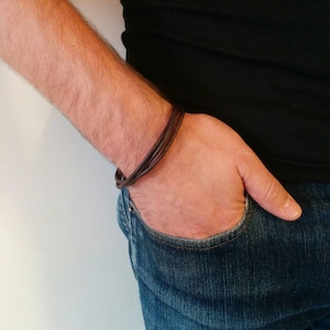 May include: A brown leather bracelet with multiple strands wrapped around a wrist.