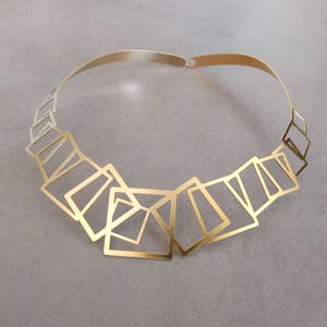 May include: A gold necklace with a geometric design made of interlocking squares.