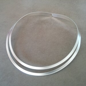 Pu&ograve; includere: Un girocollo doppio in argento. La collana &egrave; composta da due sottili bande piatte di metallo che sono unite sul retro.