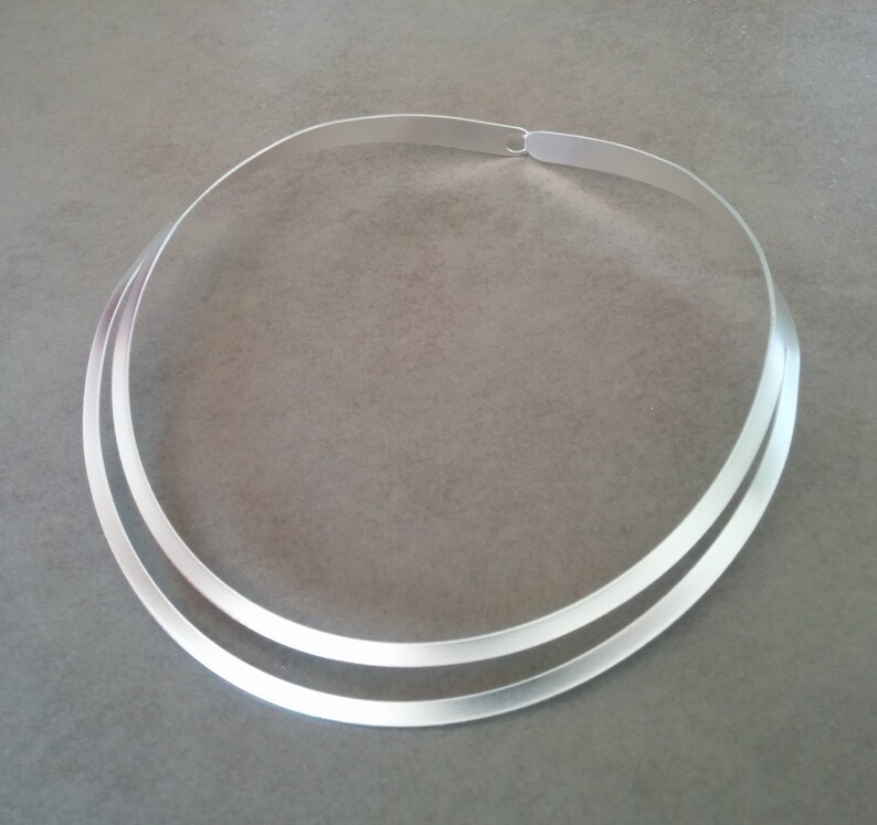 Pu&ograve; includere: Un girocollo doppio in argento. La collana &egrave; composta da due sottili bande piatte di metallo che sono unite sul retro.