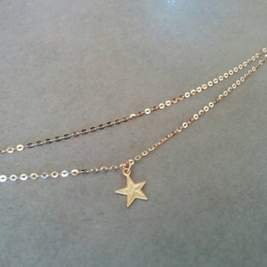 Peut inclure: Un collier en cha&icirc;ne dor&eacute;e avec un pendentif en forme d'&eacute;toile. La cha&icirc;ne est compos&eacute;e de deux brins de petits cercles li&eacute;s.