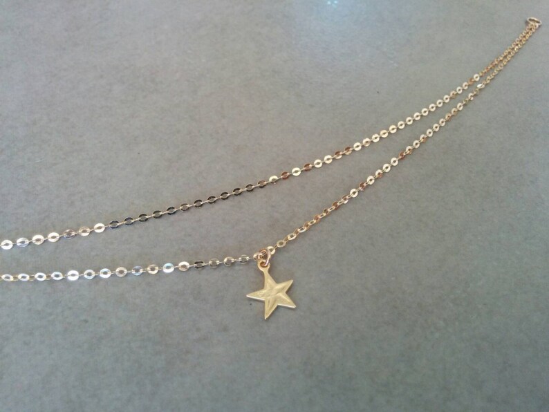 Peut inclure: Un collier en cha&icirc;ne dor&eacute;e avec un pendentif en forme d'&eacute;toile. La cha&icirc;ne est compos&eacute;e de deux brins de petits cercles li&eacute;s.