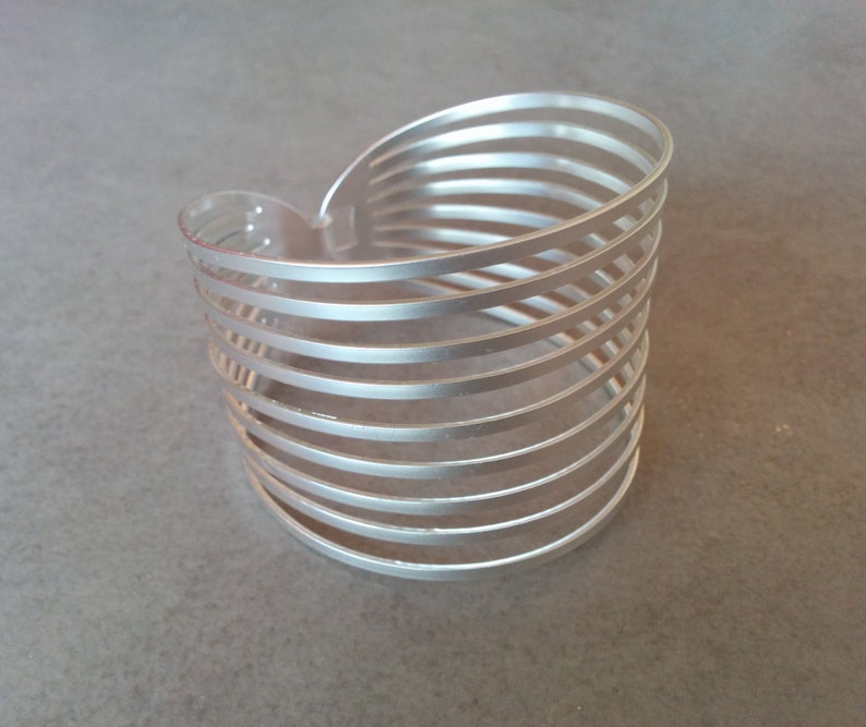 Pu&ograve; includere: Braccialetto in argento con un design a strati. Il braccialetto &egrave; realizzato con pi&ugrave; bande sottili di metallo impilate l'una sull'altra.