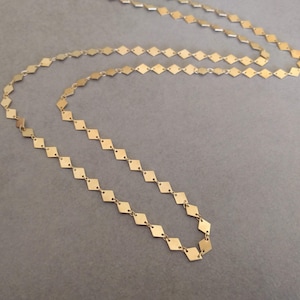 Puede incluir: Un collar de cadena de oro hecho de peque&ntilde;as piezas en forma de diamante unidas.