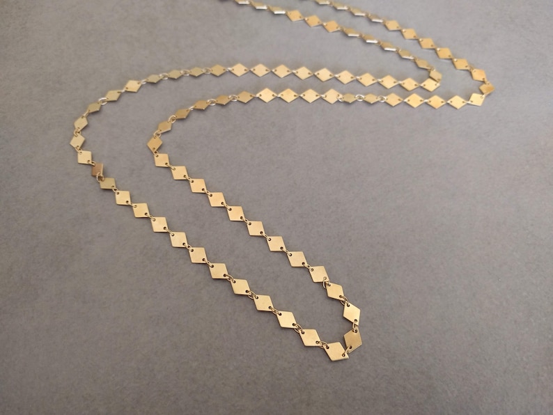 Puede incluir: Un collar de cadena de oro hecho de peque&ntilde;as piezas en forma de diamante unidas.