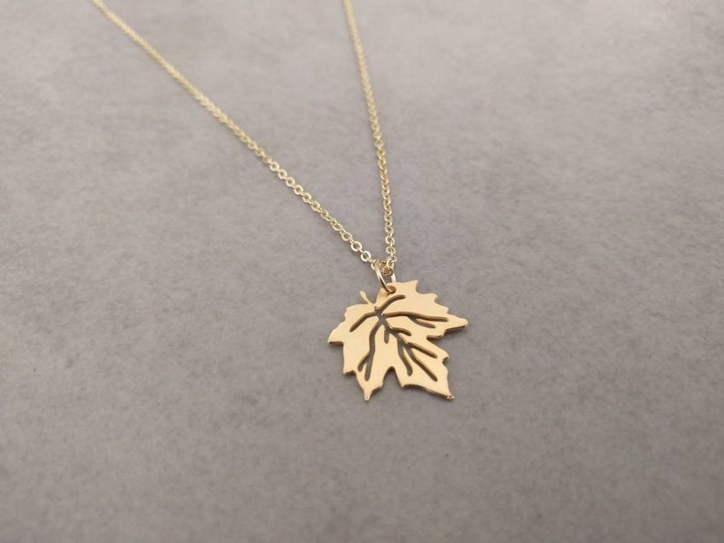 Puede incluir: Un collar de oro con un delicado colgante de hoja. La hoja est&aacute; recortada y tiene un dise&ntilde;o detallado.