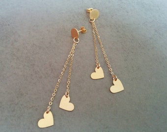 May include: Gold dangle earrings with three heart-shaped charms on each earring.