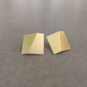 Könnte beinhalten: Ein Paar goldfarbene geometrische Ohrringe in Dreiecksform.