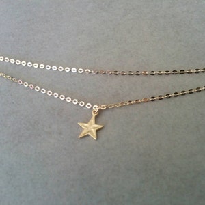Peut inclure: Un collier d&eacute;licat en cha&icirc;ne dor&eacute;e avec un petit pendentif en forme d'&eacute;toile. La cha&icirc;ne est compos&eacute;e de petits cercles li&eacute;s.