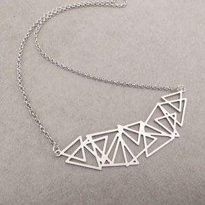 Può includere: Una collana d'argento con un ciondolo geometrico composto da più triangoli interconnessi.