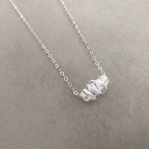May include: A silver chain necklace with a silver wire-wrapped pendant.