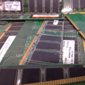 May include: A collection of green computer RAM modules with black integrated circuits and gold connectors. Some modules have white labels with text. The modules are arranged in a close-up, angled view.