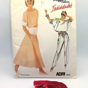 Puede incluir: Un patrón de costura vintage de Vogue Patterns Individualist, con ilustraciones de un conjunto de dos piezas. Una cremallera roja está enrollada en la parte inferior. El sobre del patrón es de color blanquecino con el texto "ADRI 1524".