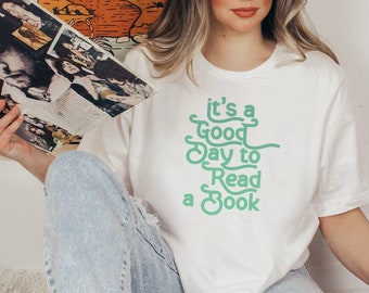 May include: White t-shirt with a green graphic that says "it's a good day to read a book".
