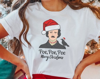 May include: White t-shirt with a graphic of Edgar Allan Poe wearing a Santa hat and holding a raven. The text "Poe, Poe, Poe Merry Christmas" is printed below the graphic.