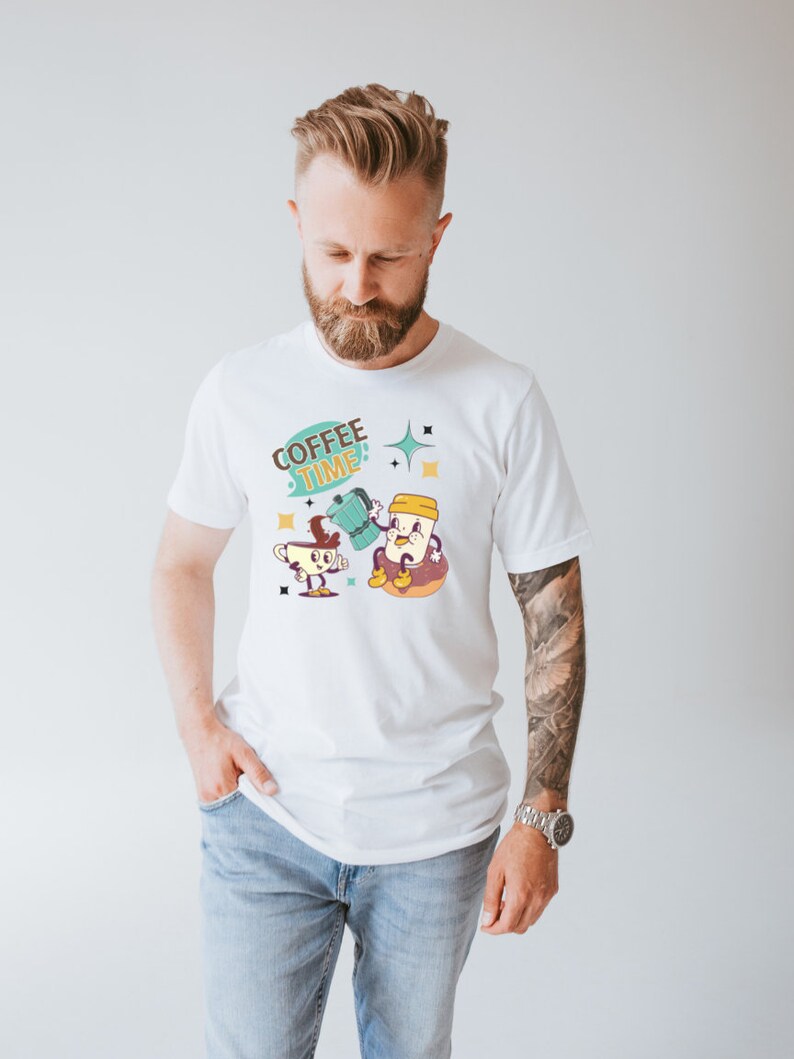 Op de afbeelding: Wit T-shirt met een cartoonillustratie van twee kopjes koffie. De tekst "COFFEE TIME" staat in een spreekballon boven de kopjes.