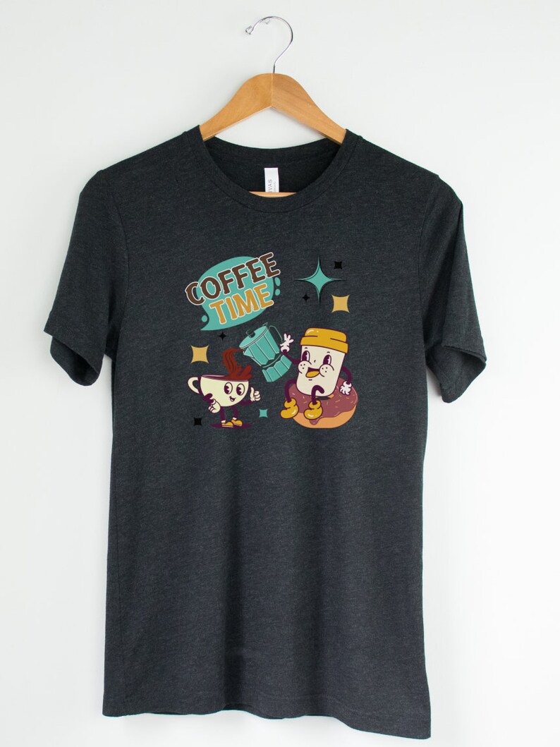 Op de afbeelding: Donkergrijs T-shirt met een afbeelding van een koffiekopje en een donut met de tekst "COFFEE TIME" in een retro stijl.