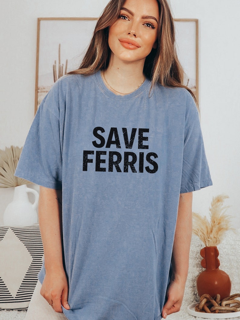 Pode incluir: Uma camiseta azul claro com o texto "SAVE FERRIS" impresso em preto.