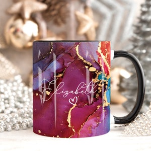 May include: A black coffee mug with a white handle. The mug has a colorful abstract design with gold accents and the name "Elizabeth" written in white with a small heart.