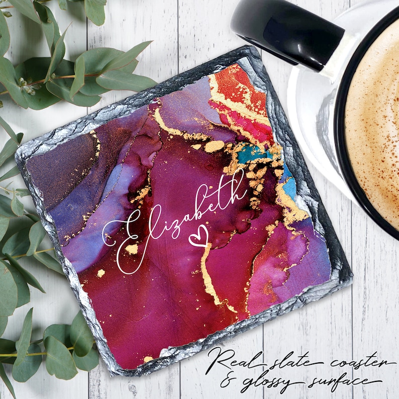 May include: A square, dark gray slate coaster with a colorful abstract design in shades of purple, blue, red, and gold. The name "Elizabeth" is written in white cursive with a small heart symbol.
