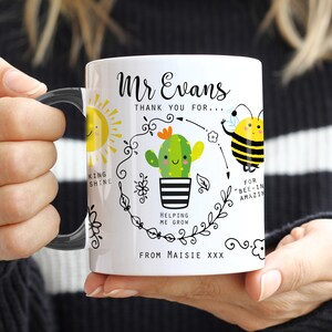 May include: White ceramic mug with a black handle. The mug features a black and white illustration of a sun, a cactus, a bee, and a flower. The text on the mug reads "Mr Evans Thank you for... King Shine Helping me grow For "Bee-in" Amazin From Maisie XXX"
