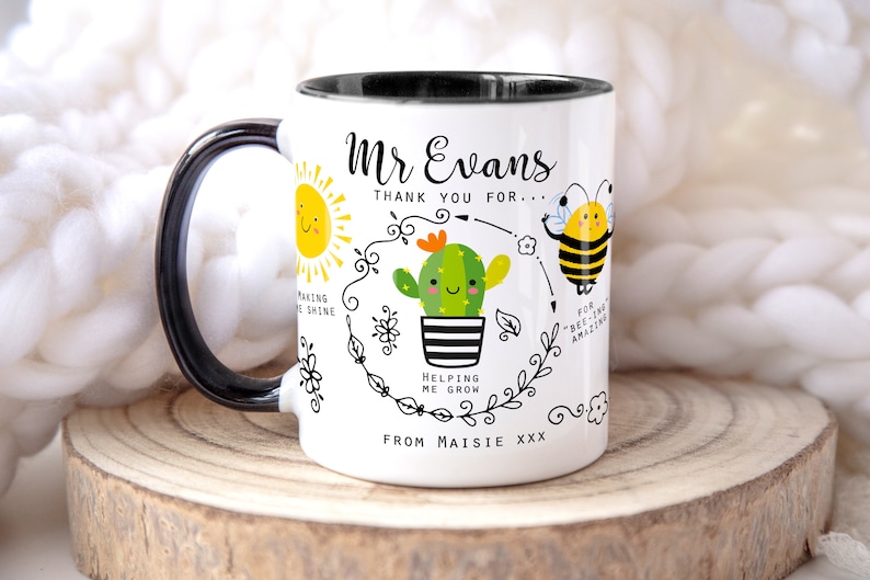 May include: White ceramic mug with a black handle and rim. The mug features a cartoon illustration of a sun, a cactus, and a bee. The text on the mug reads "Mr Evans Thank you for... Helping me grow From Maisie xxx".