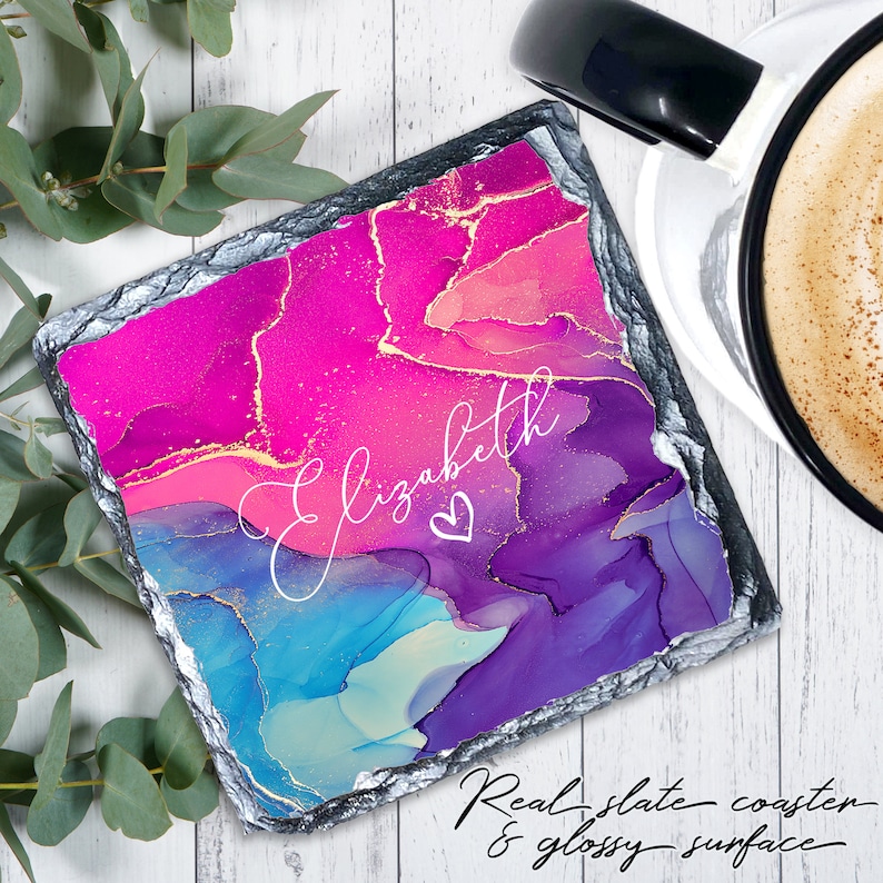 Pu&ograve; includere: Un sottobicchiere quadrato in ardesia con un design astratto rosa, blu e viola con accenti dorati. Il nome "Elizabeth" &egrave; scritto in corsivo bianco con un simbolo di cuore. "Real slate coaster & glossy surface" &egrave; scritto in corsivo nella parte inferiore dell'immagine.
